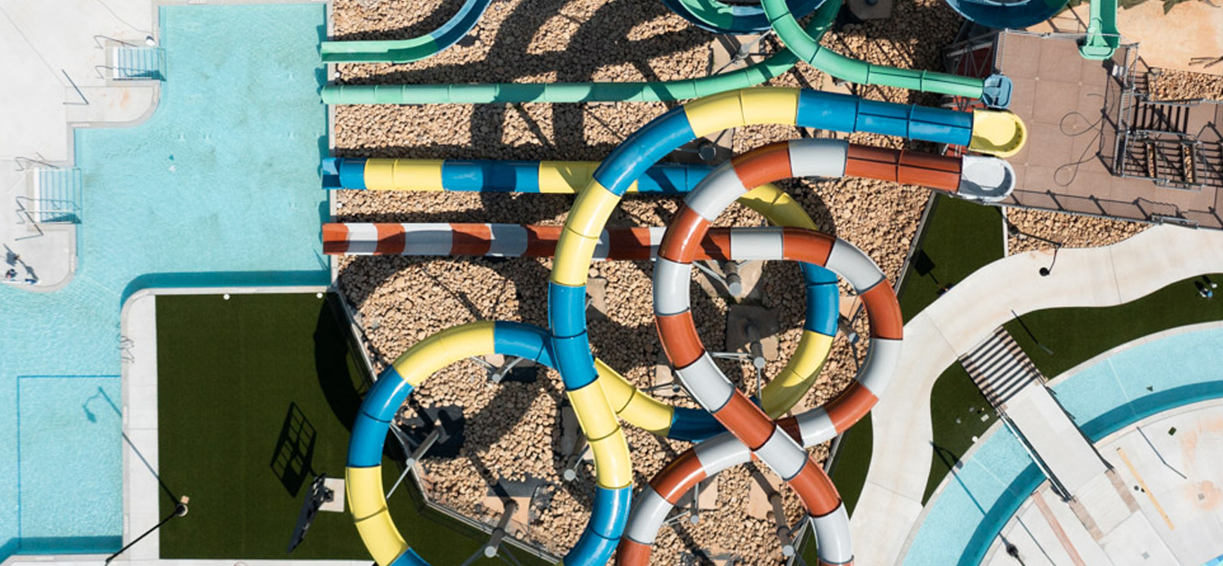 Images shows an aerial view of a new construction kiddie-pool in a greater Atlanta area water park. The waterslides are yellow and blue, red and white, and green colored. They empty into a rectangular pool..