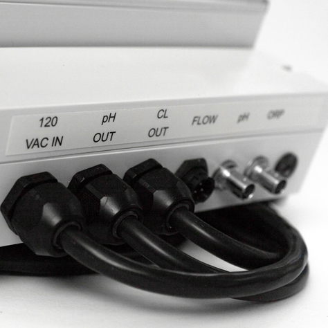 This image is a close up of the ports and connections on the mermade filter 100 series automatic chemical controller's ports and connections.It shows ports on the bottom of the off white rectangular unit that read 