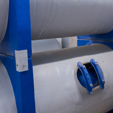 Pictured is a dual-stacked fiberglass comercial pool filter system in a filter room.