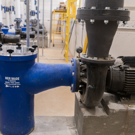 This image shows a Mer-made Filter fiberglass reducer installed on a pool filter pump and strainer basket in a filter room.